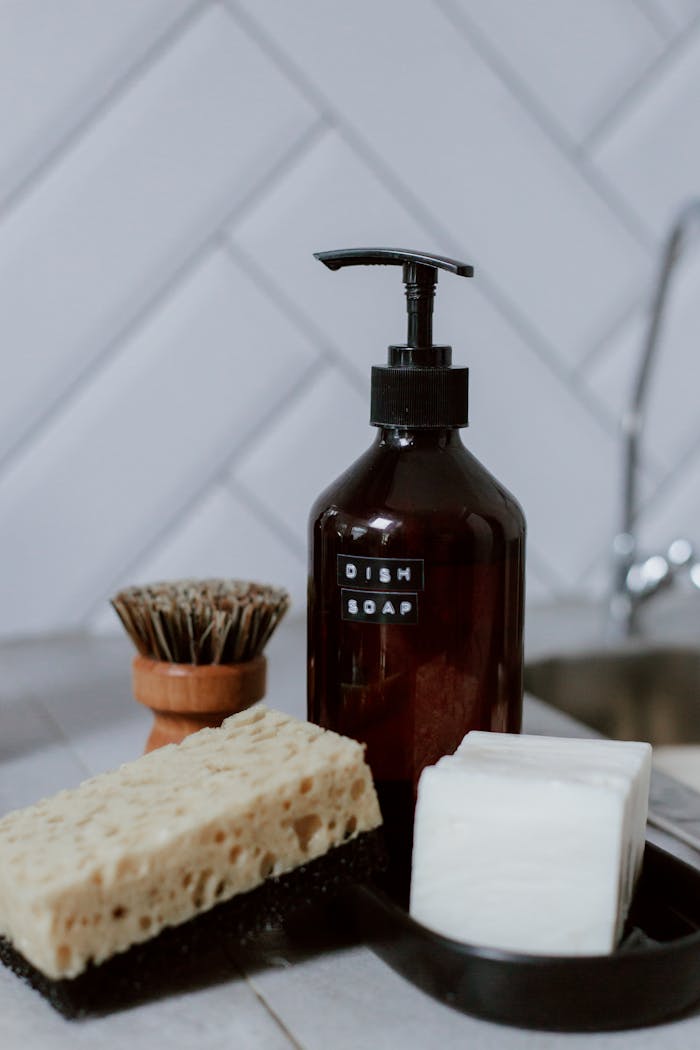 A stylish arrangement of eco-friendly kitchen cleaning products on a countertop with a chevron tile backsplash.